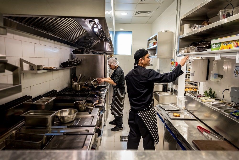 Equipe de cozinheiros preparando embalagens de delivery em uma dark kitchen, aplicando uma estratégia de marketing focada em eficiência e apresentação de marca.