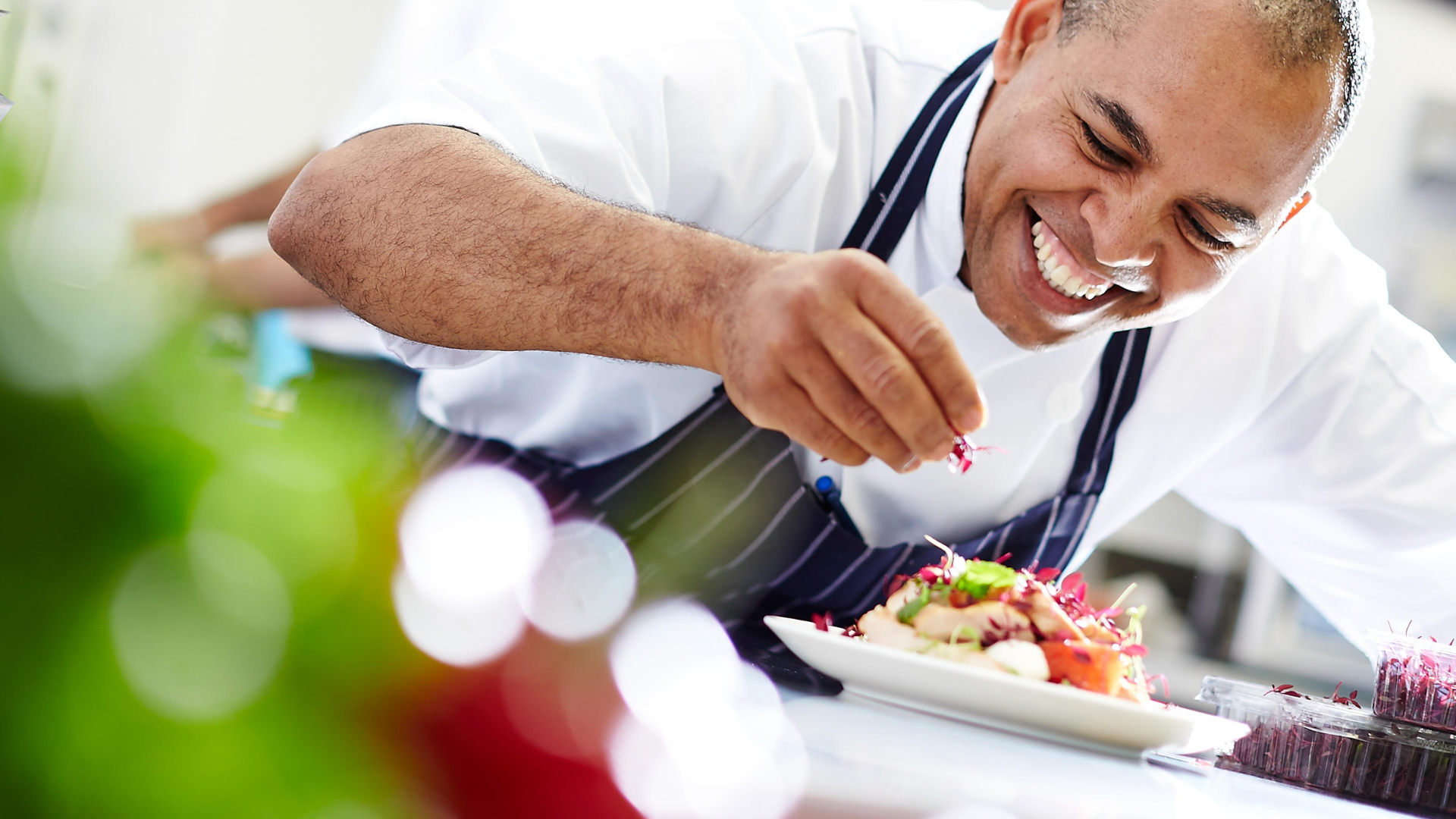 Chef sorridente finalizando prato gourmet – exemplo de como atrair clientes para chef com apresentação profissional e carisma.
